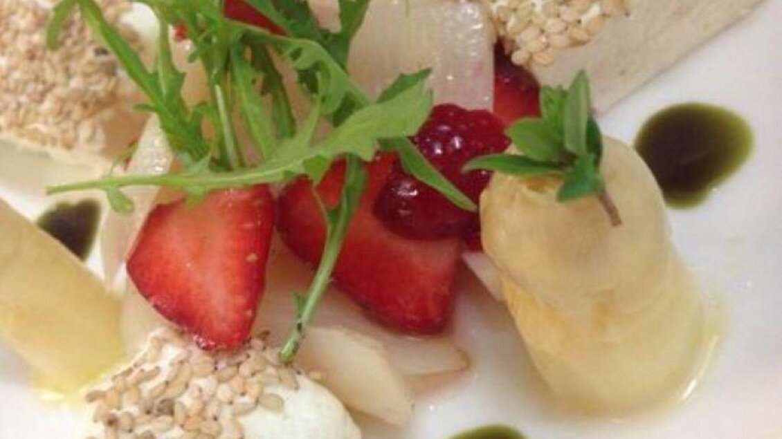 Ein kunstvoll angerichteter Teller mit verschiedengeschichtetem Dessert. Die Zutaten umfassen frische Erdbeeren, Sesam und Kräuter. | © Wassermann-Wirt