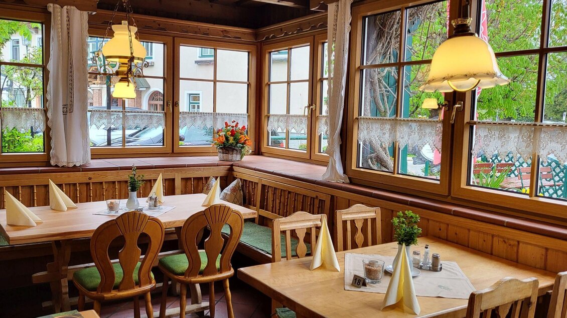 Ein gemütliches Restaurant mit Holzmöbeln und großen Fenstern. Die Tische sind liebevoll gedeckt und der Raum wirkt einladend und hell. | © Petra Kirchschlager