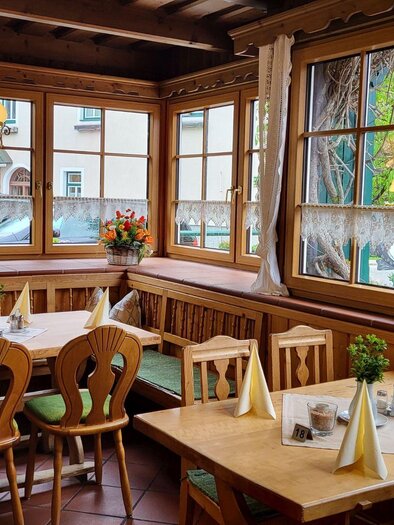 A cozy restaurant with wooden furniture and large windows. The tables are lovingly set, and the room feels inviting and bright. | © Petra Kirchschlager