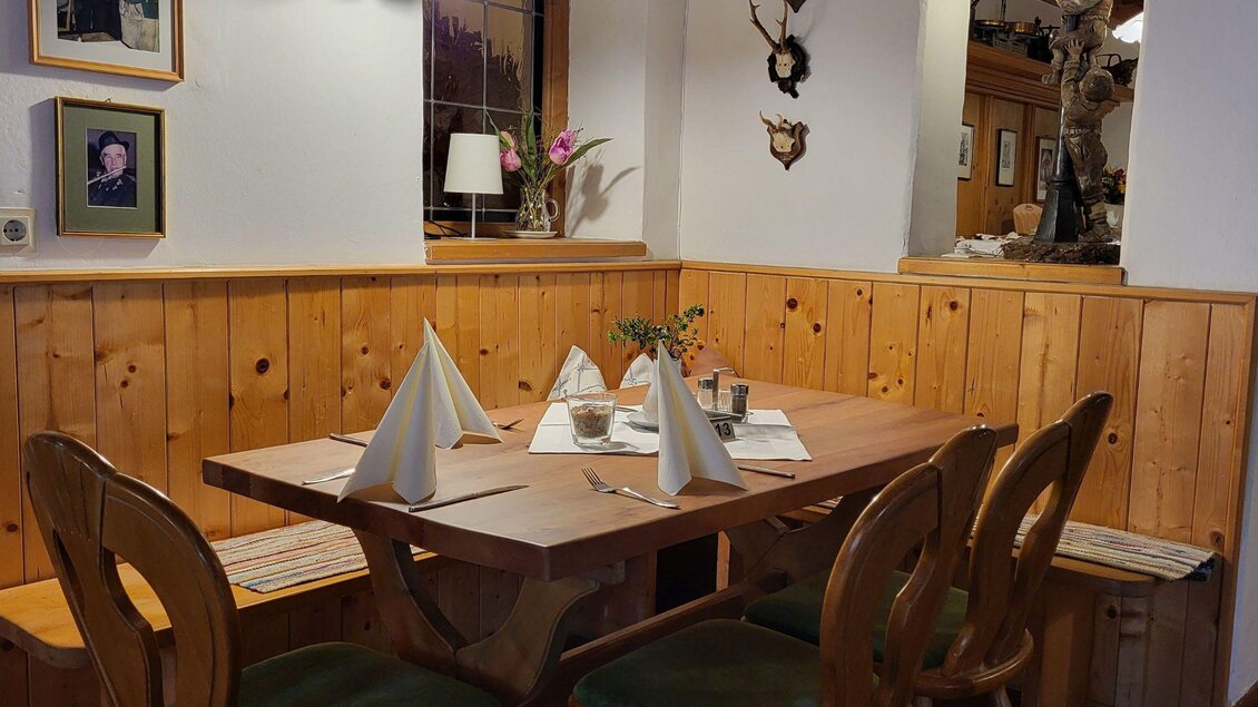 Ein gemütlicher Tisch in einem Restaurant mit Holzverkleidung. Die Tafel ist schön gedeckt und es hängen Rahmen an der Wand. | © Petra Kirchschlager