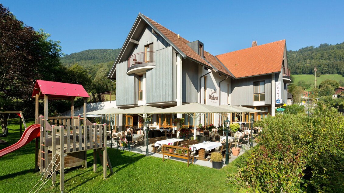 Ein gemütliches Hotel mit einem einladenden Restaurant im Freien. Im Vordergrund befindet sich ein Spielplatz für Kinder. | © TV Region Graz - René Vidalli