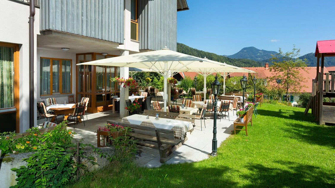 Ein einladender Außenbereich mit Tischen und Stühlen unter Sonnenschirmen. Im Hintergrund sind grüne Wiesen und Berge zu sehen. | © TV Region Graz - Rene Vidalli