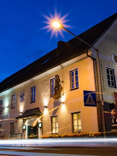 A historic building with a brightly lit facade at night. It is located on a street and has decorative elements on the wall. | © Gasthof Egidiwirt