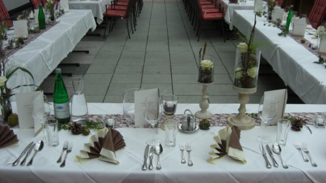 Ein festlich gedeckter Tisch im Freien mit weißen Tischdecken und dekorativen Elementen. Stühle sind um den Tisch herum angeordnet, bereit für eine Veranstaltung. | © Gasthof Forellenhof