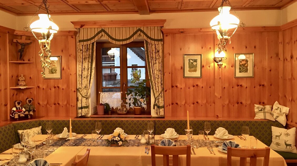 Ein gemütlicher Speisesaal mit Holzverkleidungen und einem langen Tisch. Der Raum ist dekoriert mit Kerzen und Bildern, und ein Fenster bietet Blick ins Freie. | © Gasthof Franzbauer