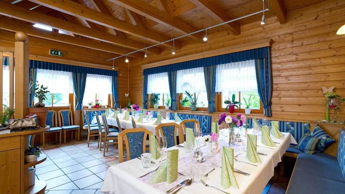 Ein gemütliches Restaurant mit Holzdekor und großen Fenstern. Der Tisch ist für eine Feier festlich gedeckt, umgeben von Pflanzen. | © TV Region Graz - René Vidalli