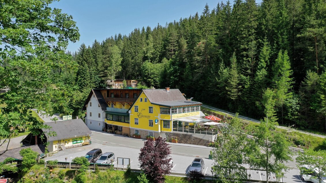 Ein malerisches Hotel inmitten von Bäumen und Natur. Die gelbe Fassade des Gebäudes strahlt im Sonnenlicht. | © Kump