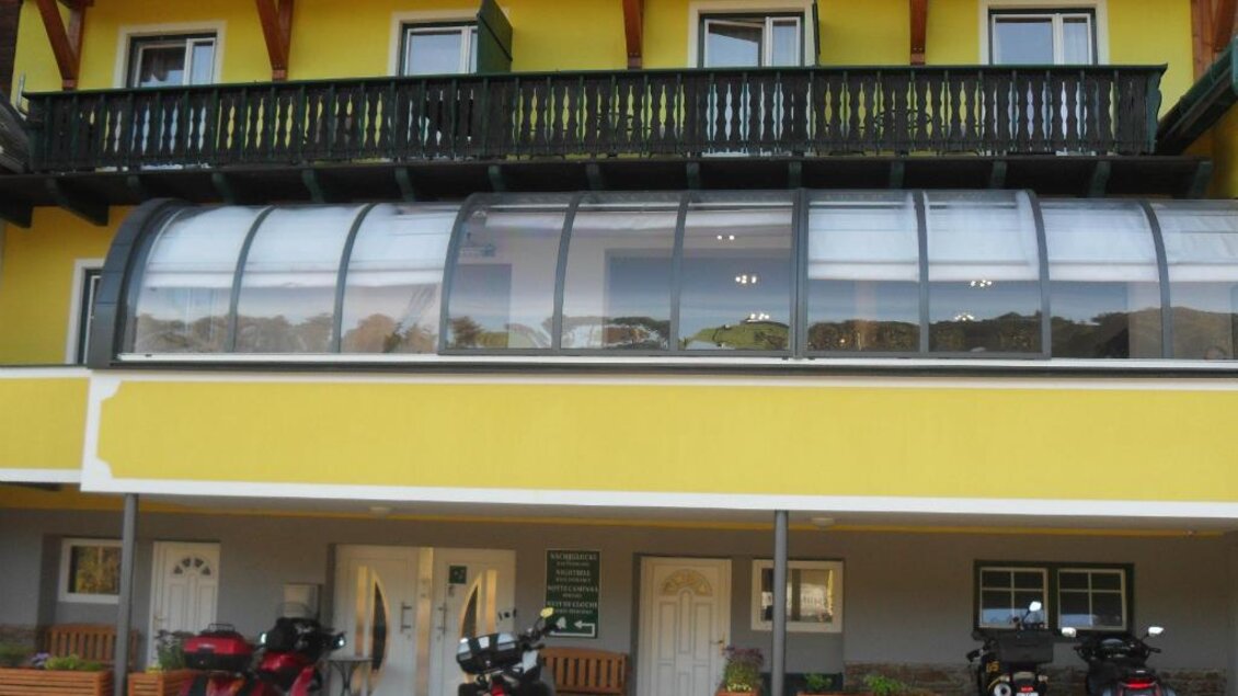 Ein gelbes Gebäude mit einem Balkon und großen Fenstern. Vor dem Gebäude stehen mehrere Motorräder. | © Gasthof Klug "Zum Ehrensepp"