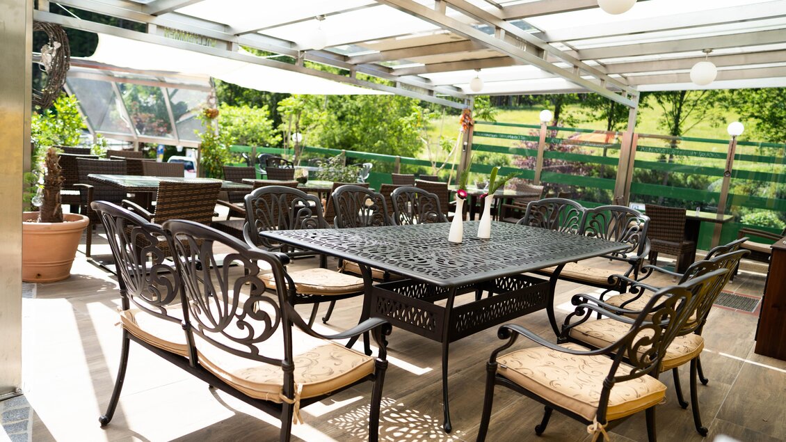 Ein einladender Außenbereich mit einem großen Tisch und eleganten Stühlen. Umgeben von grünem Gras und natürlichem Licht. | © Steirische Rucksackdörfer-KumpPhotography