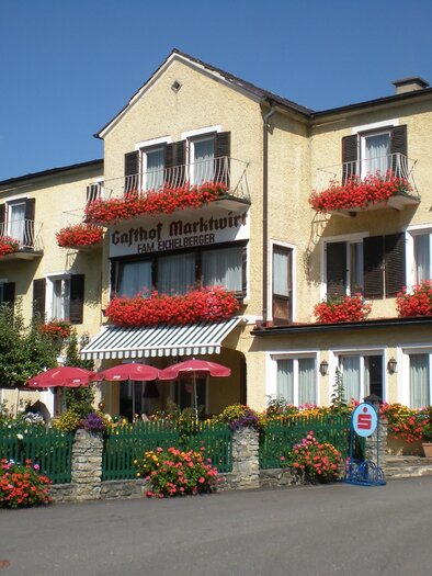 A charming inn with blooming balcony boxes. The entrance area is surrounded by colorful flowers and invites guests to linger.