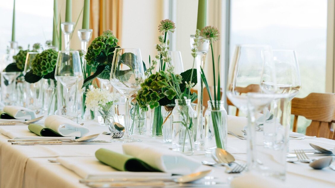 Ein elegant gedeckter Tisch mit Glasgeschirr und frischen Blumen. Die grüne Farbpalette sorgt für eine frische und einladende Atmosphäre. | © Martinhof
