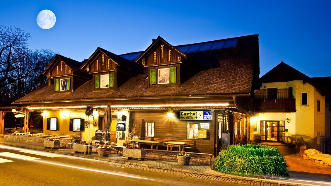Ein traditionelles Gasthaus bei Nacht, beleuchtet von warmen Lichtern. Der klare Himmel zeigt einen schönen Vollmond. | © Gasthof Kranerwirt