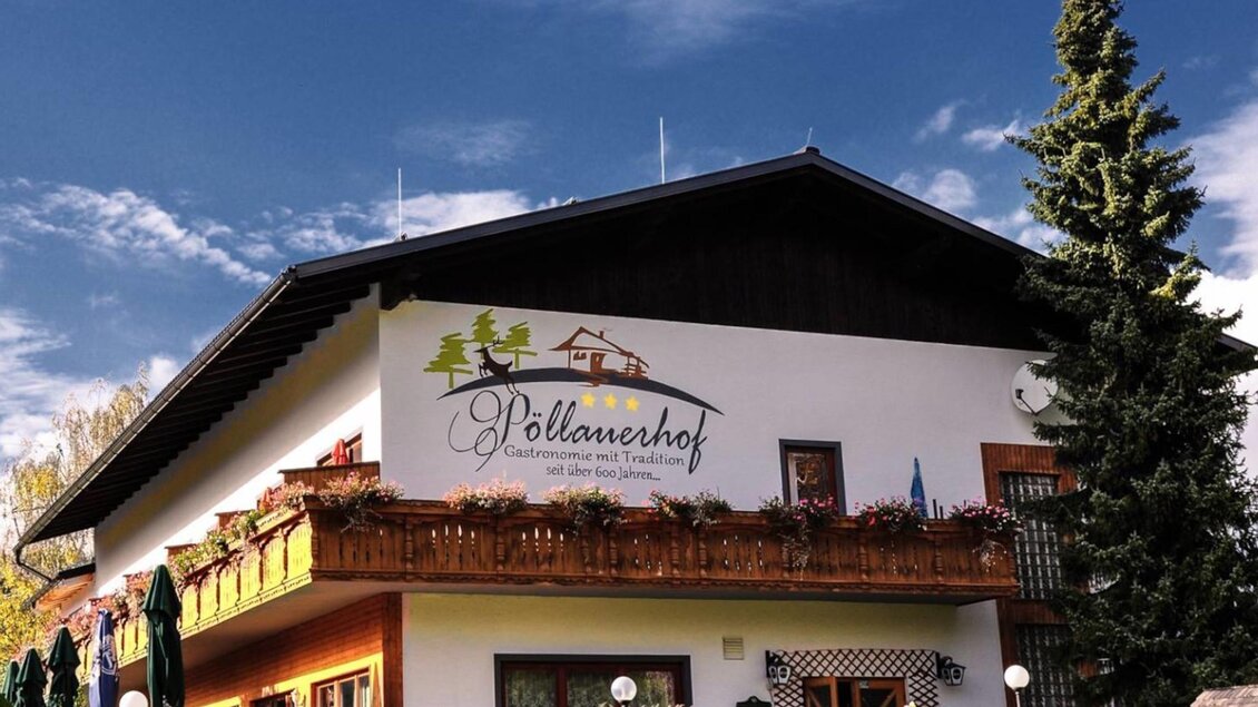 Ein charmantes Haus mit einem Balkon voller Blumen und einer einladenden Fassade. Der Himmel ist klar und die Umgebung ist grün und gepflegt. | © Gasthof Pöllauerhof