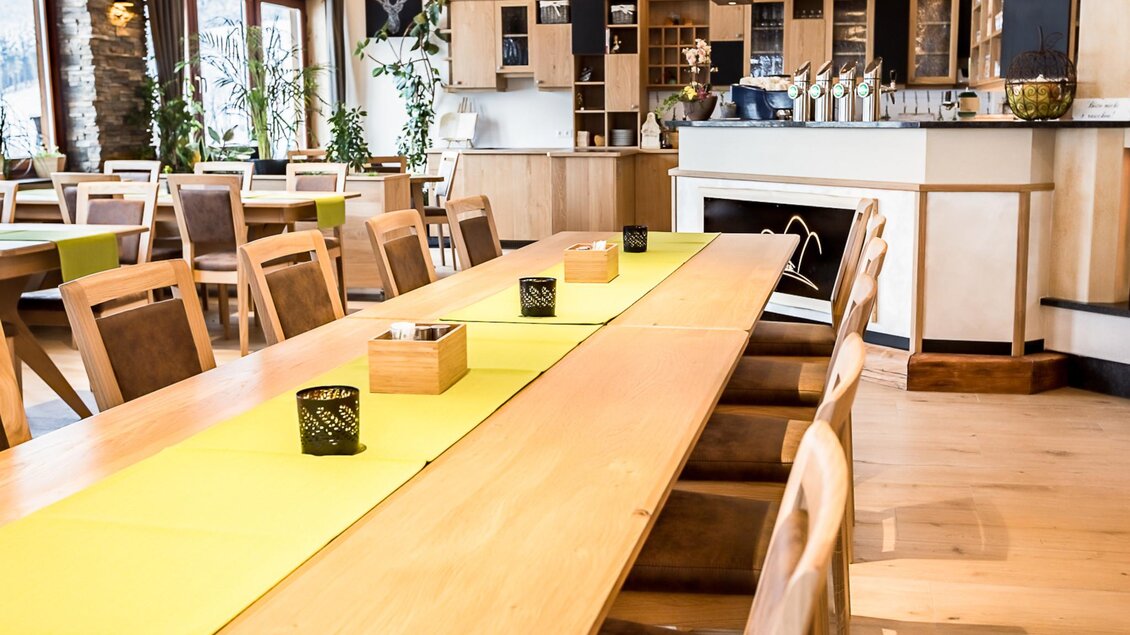 Ein modernes Restaurantinterieur mit einem langen Holz-Esstisch und stühlen. Die Wände sind mit Pflanzen dekoriert, und die Umgebung wirkt einladend und hell. | © Gasthof Pöllauerhof