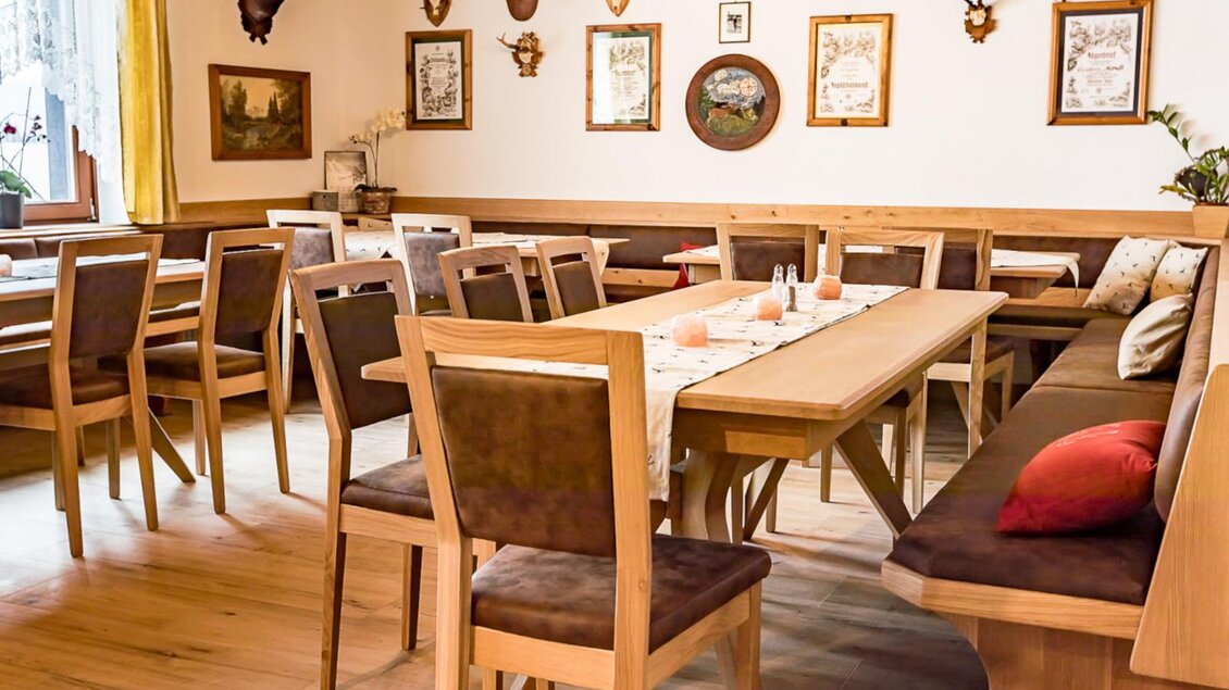 Ein gemütliches Restaurant mit Holzstühlen und -tischen. Die Wände sind mit einem Jagdmotiv und verschiedenen Gemälden dekoriert. | © Gasthof Pöllauerhof
