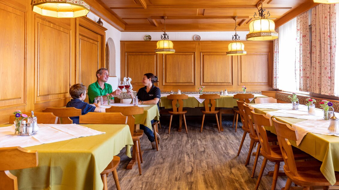 Ein gemütliches Restaurant mit Holzmöbeln und warmem Licht. Eine Familie sitzt zusammen am Tisch und genießt ihre Zeit. | © Lipizzanerheimat | Harry Schiffer