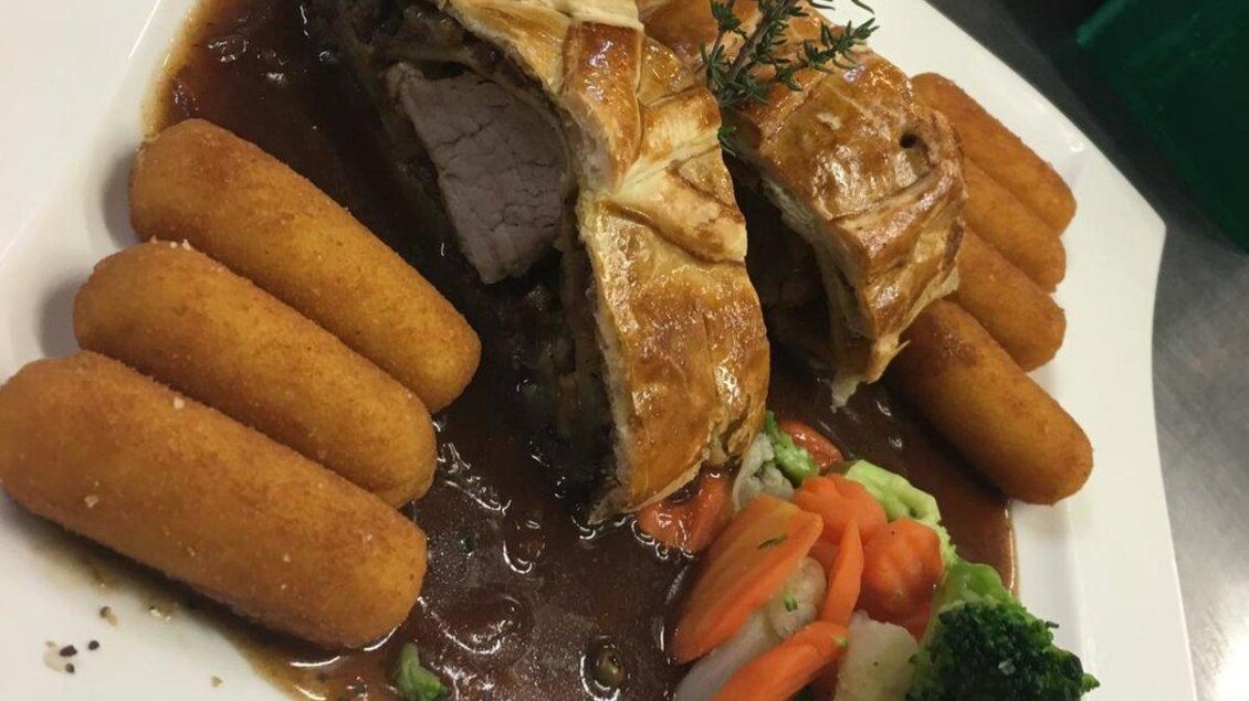 Ein ansprechend serviertes Gericht mit gefülltem Teig und einer Sauce. Dazu gibt es Gemüse und knusprige Beilagen. | © Fam. Reinisch