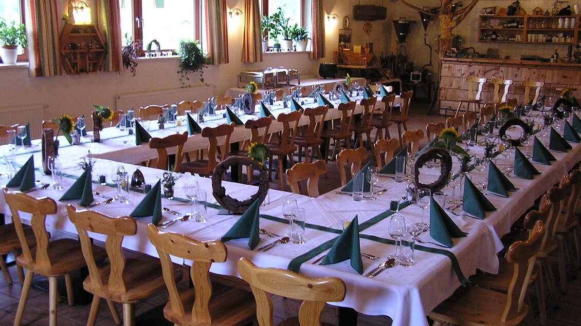 Ein festlich gedeckter Tisch in einem gemütlichen Raum. Die Tischdeko umfasst grüne Servietten und Blumen, ideal für eine Feier. | © Gasthof Rieseralm