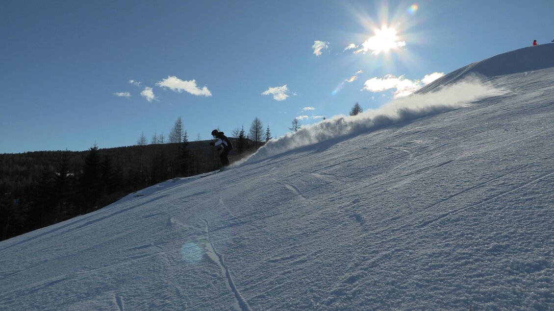 Ein Skifahrer fährt über eine schneebedeckte Piste. Die Sonne scheint hell am blauen Himmel. | © Gasthof Rieseralm