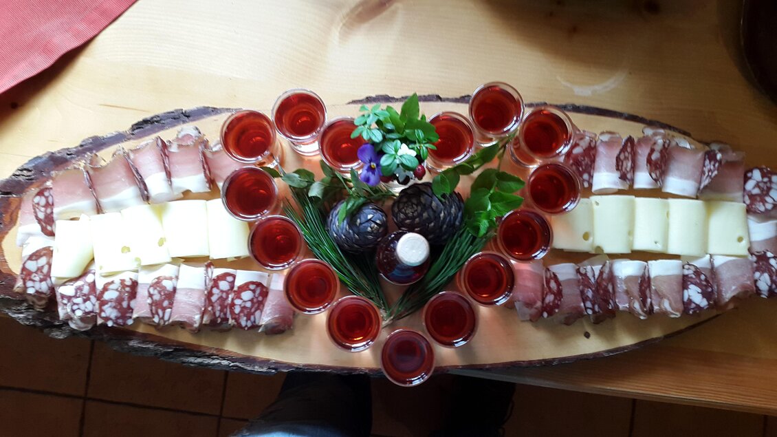 Eine schöne Platte mit Wurst und Käse, dekoriert mit kleinen Gläsern und frischen Kräutern. Die Anordnung ist ansprechend und einladend. | © Gasthof Rieseralm