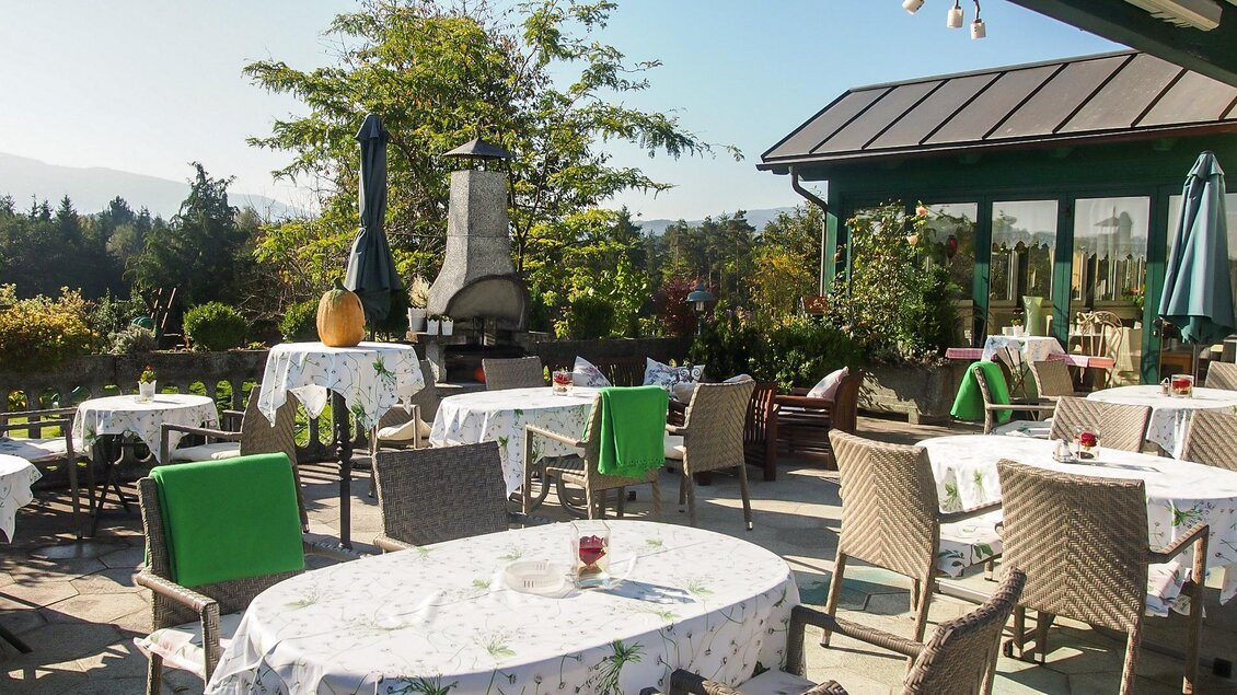 Ein schöner Außenbereich eines Restaurants mit gedeckten Tischen und Stühlen. Die Umgebung ist grün und sonnig, ideal für eine entspannte Mahlzeit im Freien. | © GH Safran Filatsch