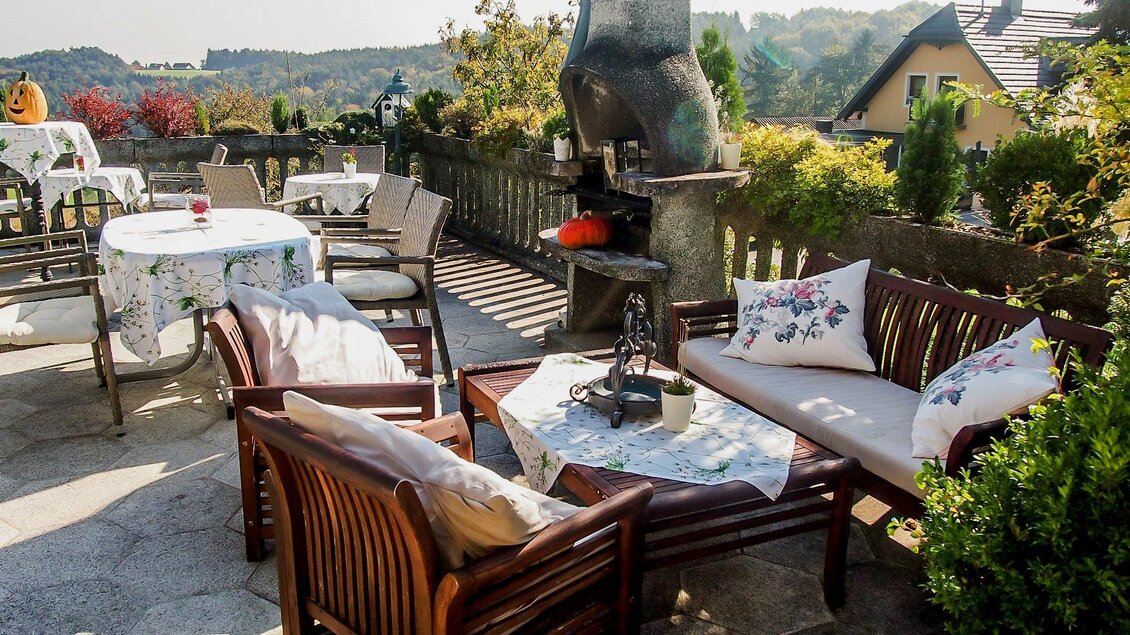 Eine gemütliche Terrasse mit Holzmöbeln und einem Grill. Im Hintergrund sind schöne Pflanzen und die Aussicht auf die Landschaft zu sehen. | © GH Safran Filatsch