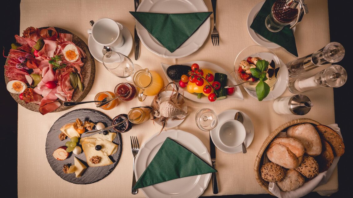 Ein reichhaltiger Frühstückstisch mit verschiedenen Speisen, einschließlich Wurst, Käse, Obst und Brötchen. Die Tischeindeckung ist elegant mit weißen Tellern und grünen Servietten. | © GH Schäffer_Neuberg (C) Seiser_Karner
