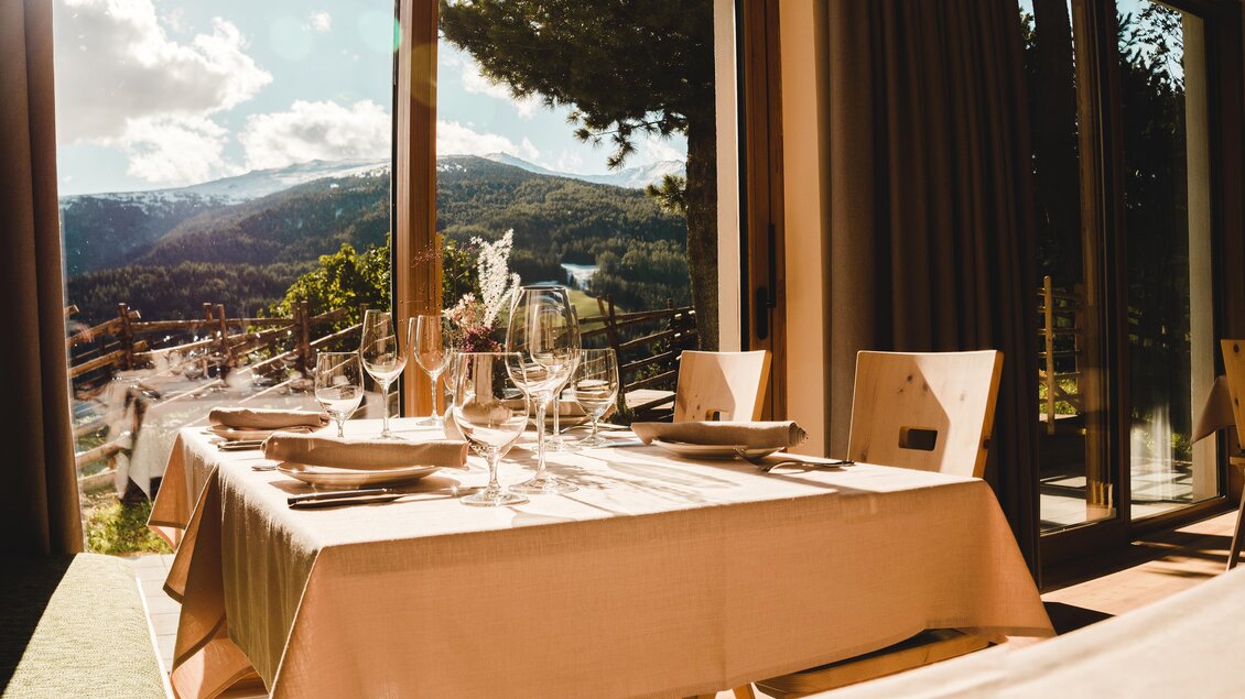 Ein elegant gedeckter Tisch mit Gläsern und Besteck. Im Hintergrund sind Berge und eine grüne Landschaft sichtbar. | © Gasthof und Pension Seetalbllick