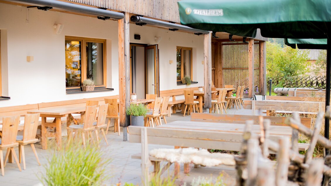 Ein einladendes Restaurant mit Holzterrasse und Tischen im Freien. Die Umgebung ist grün und freundlich gestaltet. | © Erlebnisregion Murtal