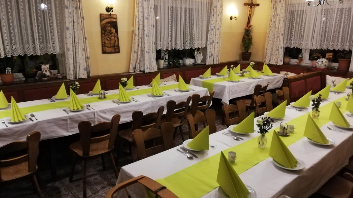 Ein festlich gedeckter Saal mit langen Tischen und leuchtend grünen Servietten. Die Wände sind mit Vorhängen und Dekorationen versehen, die eine gemütliche Atmosphäre schaffen. | © Tourismusverband Murau