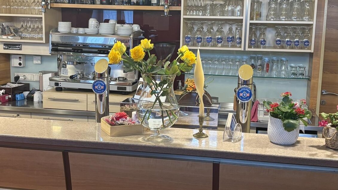 Eine Bar mit modernen Möbeln und einer Auswahl an Getränken. Auf dem Tresen stehen Blumen und dekorative Pflanzen. | © Strohmeier