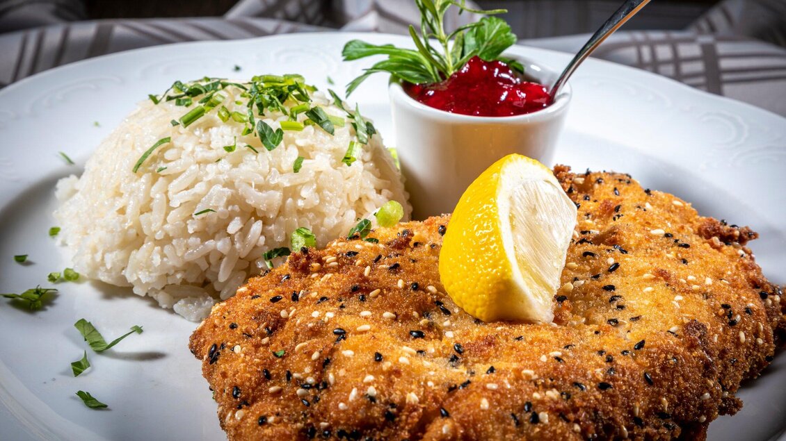Ein knuspriges Schnitzel mit Zitrone und einer Portion Reis. Dazu gibt es eine Schale mit roter Sauce. | © TV Region Graz - Lunghammer