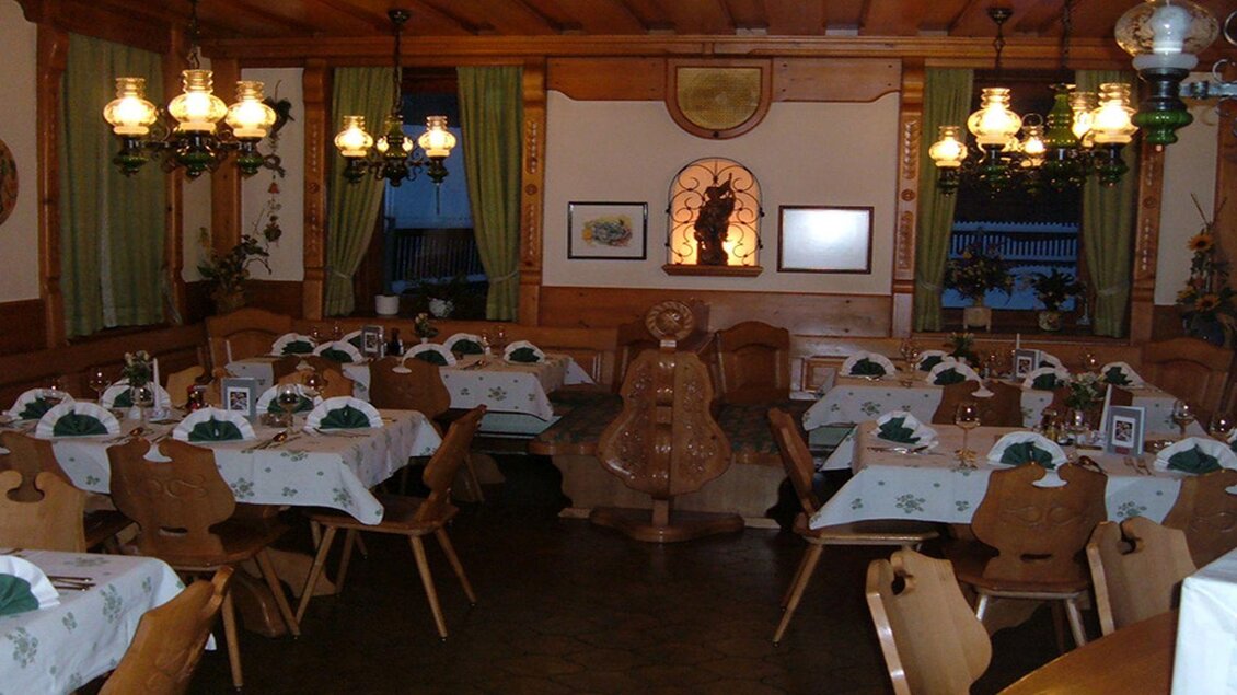 Ein einladendes Restaurant mit Holzmöbeln und dekorierten Tischen. Die warmen Lichter schaffen eine gemütliche Atmosphäre.