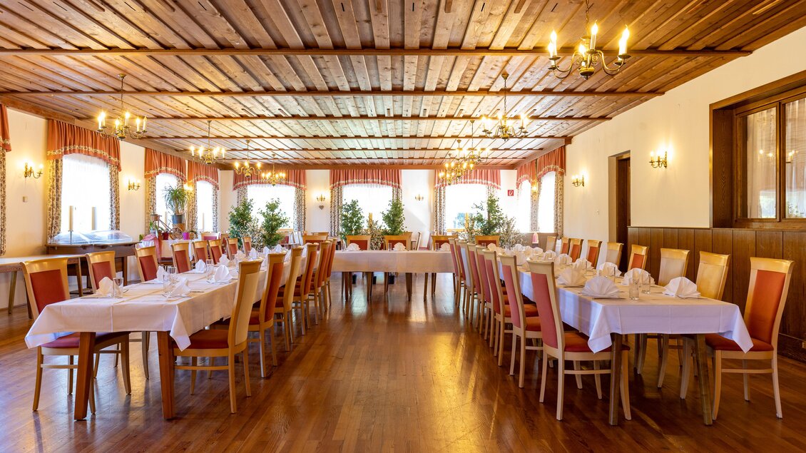 Ein einladender Veranstaltungsraum mit langen Tischen und Stühlen. Die warme Holzdecke und die Fenster sorgen für eine freundliche Atmosphäre. | © Lipizzanerheimat | Harry Schiffer