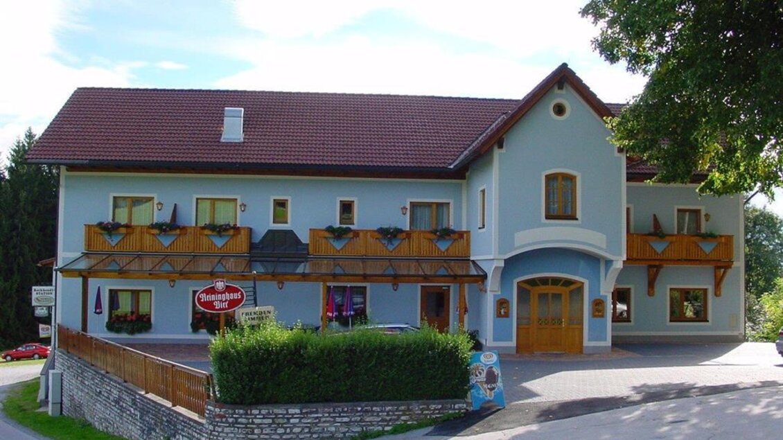 Ein charmantes Gebäude mit einem hellblauen Anstrich und braunen Holzbalkonen. Umgeben von Grün, lädt es zum Verweilen ein. | © Gasthof Wiendl