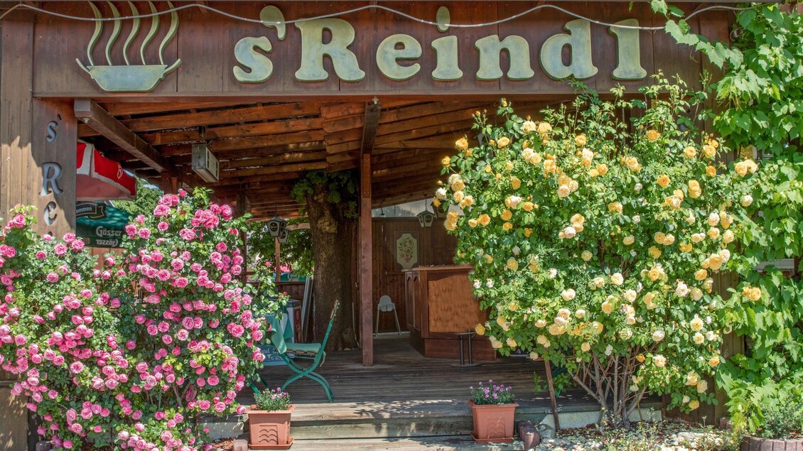 Ein einladendes Restaurant mit dem Namen "s'Reindl". Bunte Blumen schmücken den Eingangsbereich und schaffen eine freundliche Atmosphäre. | © Gasthof s'Reindl