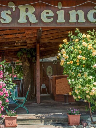 An inviting restaurant named "s'Reindl". Colorful flowers adorn the entrance area, creating a friendly atmosphere. | © Gasthof s'Reindl