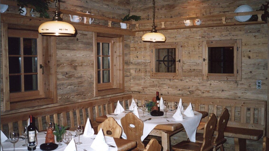 Ein rustikales Restaurant mit Holzwänden und einem gemütlichen Essbereich. Tische sind mit weißen Tischdecken und Faltservietten gedeckt. | © Fam. Engleitner