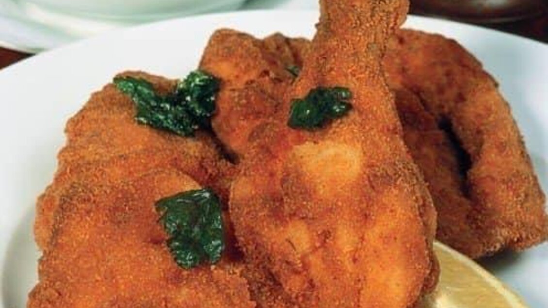 Frittierte Hähnchenteile auf einem Teller, garniert mit frischen Kräutern und einer Zitronenscheibe. Ein köstliches, ansprechendes Gericht. | © Gaststätte Franz August