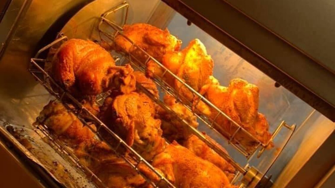 Ein Brathähnchen-Rotisserie mit mehreren goldbraun gebratenen Hähnchen. Die Hähnchen sind in einem Heizofen präsentiert. | © Gaststätte Franz August