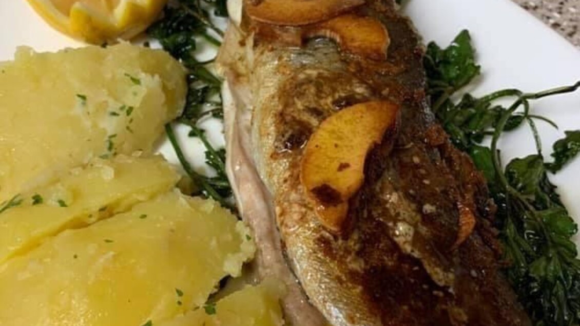 Ein gegrillter Fisch mit knuspriger Haut, serviert mit Kartoffeln und Petersilie. Dazu eine Zitronenscheibe und etwas Kaviar. | © Gaststätte Franz August