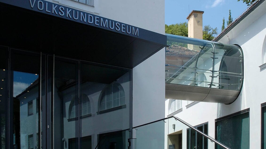 Eingang des Volkskundemuseums mit moderner Glaspromenade, die die historischen Gebäude miteinander verbindet. | © Volkskundemuseum