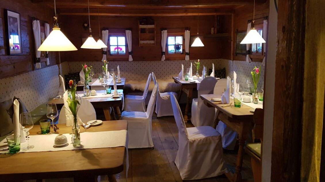 Ein einladendes Restaurant mit Holztischen und stilvollen Stühlen. Die Tische sind hübsch dekoriert mit Blumen und Kerzenlicht. | © Dominik Utassy