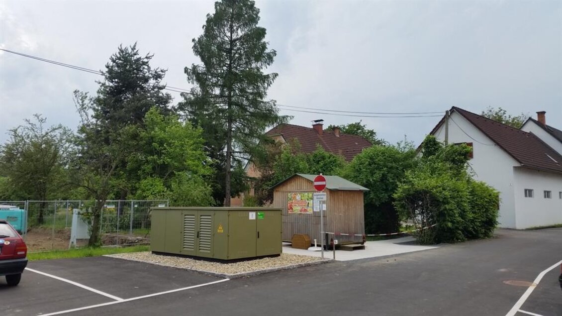 Ein kleiner Bereich mit einem elektrischen Transformator und einem Holzhaus in einer Wohngegend. Umgeben von Bäumen und einem Parkplatz. | © Tschernko