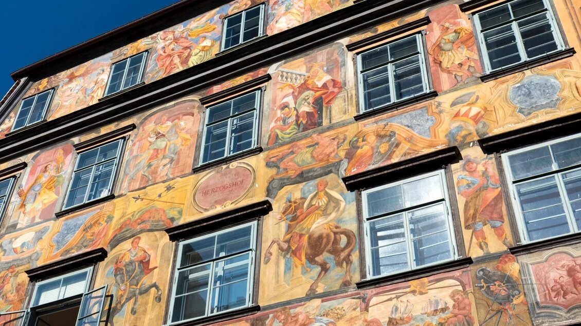 Wandgemälde mit Szenen und Kartusche „Herzogshof“ am Gemalten Haus in Graz | © Graz Tourismus-Harry Schiffer