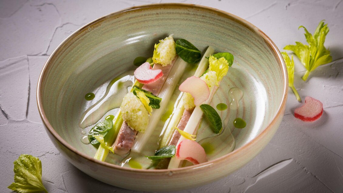 Ein elegantes Gericht in einer flachen Schüssel. Es besteht aus frischen Zutaten wie Gemüse, Kräutern und einer feinen Soße. | © Genießerei am Markt