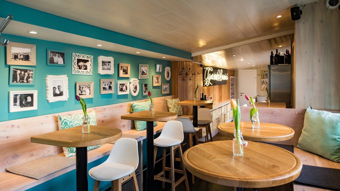 Ein modernes Café mit einer einladenden Atmosphäre. An den Wänden hängen Fotos, und die Tische sind aus hellem Holz. | © Genießerei am Markt