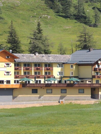 Ein modernes Hotel inmitten von grünen Bergen. Es hat Balkone mit Blick auf die Landschaft und eine einladende Architektur. | © Hotel Hierzegger