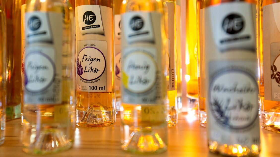 Eine Auswahl von Likörflaschen steht auf einem Tisch. Die Flaschen haben verschiedene Geschmacksrichtungen und leuchten warm in der Beleuchtung. | © Region Graz - Harry Schiffer