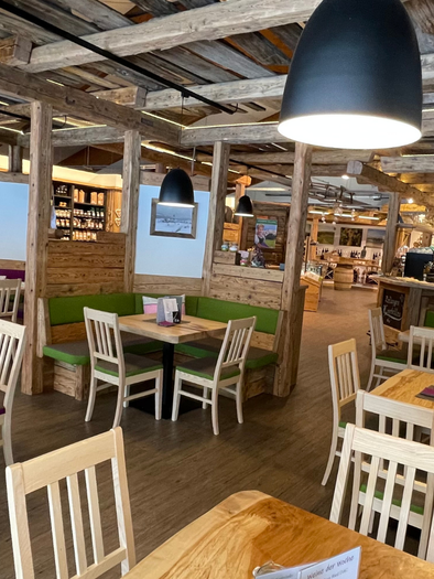 A cozy restaurant with wooden furniture and colorful benches. The atmosphere is warm and inviting, perfect for a relaxed meal. | © Melanie Jos